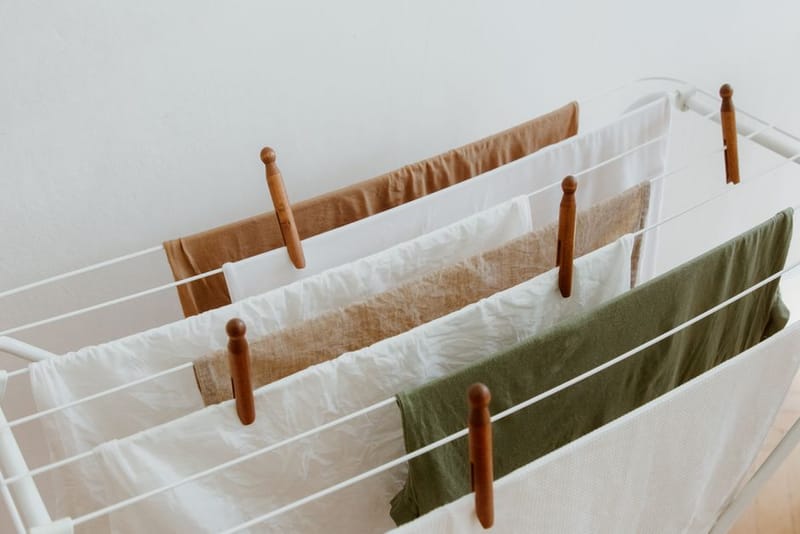 Laundry pegged on a white drying rack indoors against a white wall