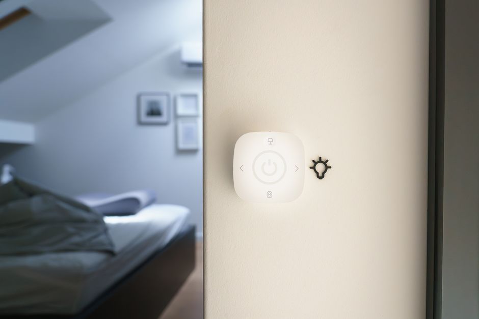 Small smart button-pusher device mounted on a light switch